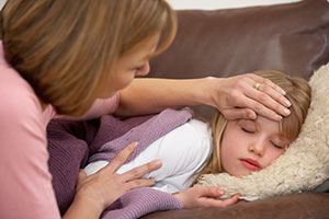 Sick girl with mom checking her forehead