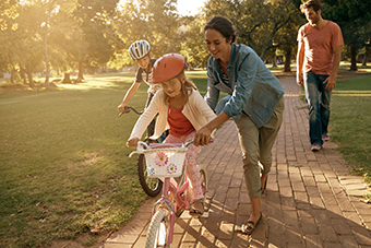 Parents teaching kids to ride bikes