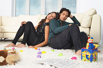 Tired parents sitting on the floor with kids' toys