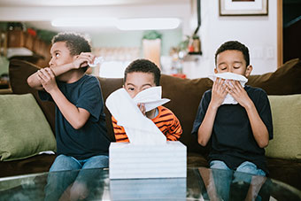 Three boys sneezing
