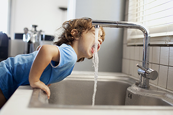 Boy drinking water from the faucet
