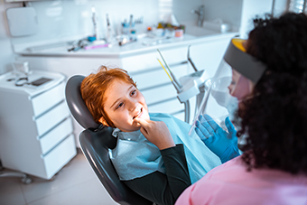 boy in dentist chair pointing at tooth