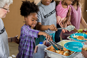 Young girl serving food at soup kitchen