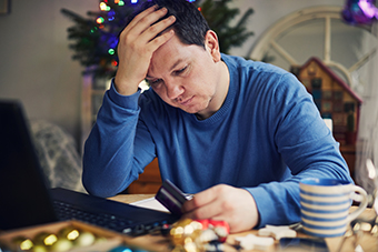 stressed dad at the computer holding a credit card during the holidays