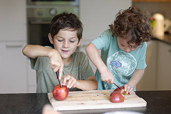 Two young boys cutting apples